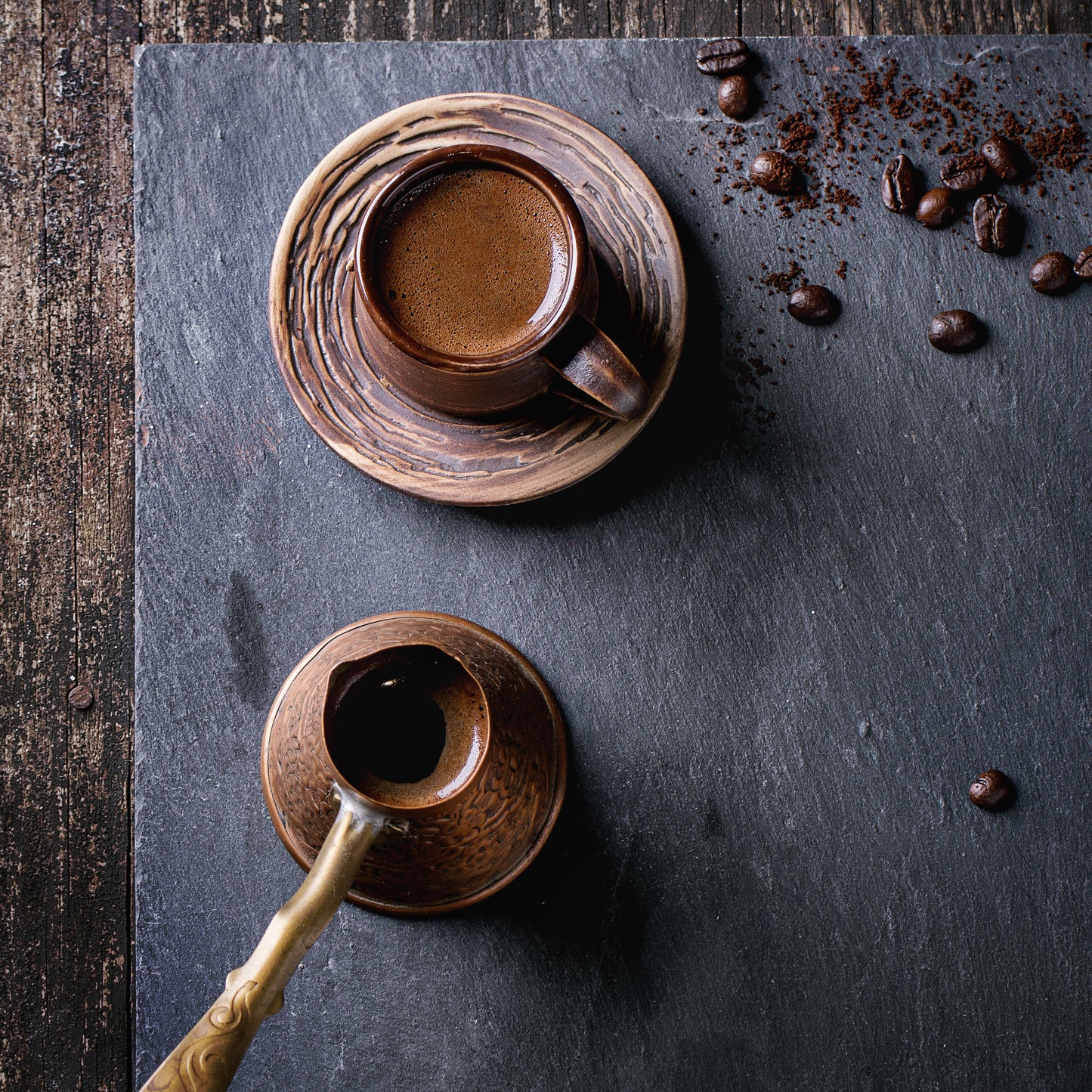 Ellie's East African dark roast espresso in a cup with coffee beans in the background and a Turkish  cezve.